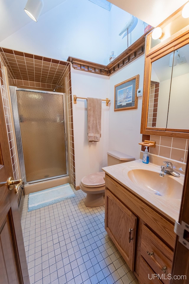 bathroom with tile patterned floors, toilet, a shower with shower door, and vanity