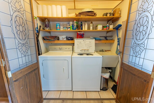 clothes washing area featuring light tile patterned floors and washing machine and clothes dryer