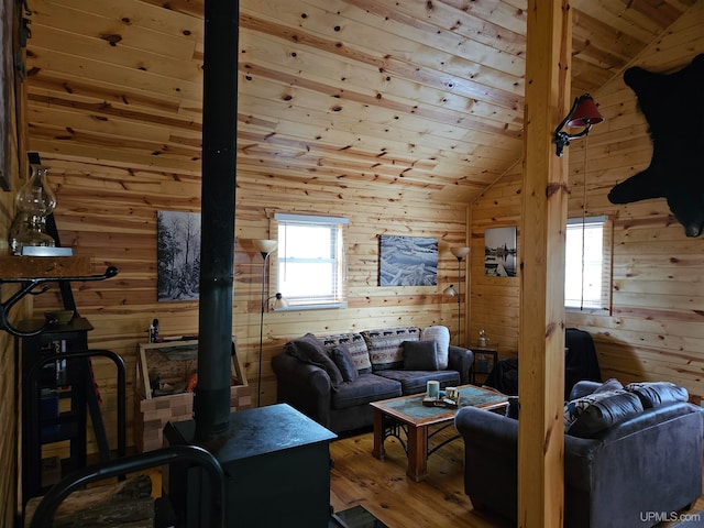 living room with lofted ceiling, hardwood / wood-style floors, wood walls, and plenty of natural light