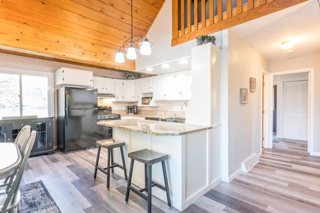 kitchen featuring light hardwood / wood-style floors, tasteful backsplash, white cabinetry, and refrigerator