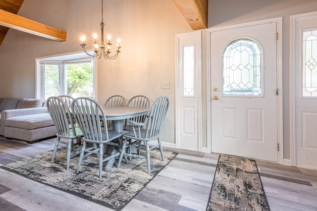 dining area with lofted ceiling with beams, an inviting chandelier, and hardwood / wood-style flooring