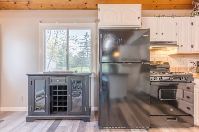 kitchen featuring hardwood / wood-style flooring, tasteful backsplash, gas stove, white cabinetry, and black refrigerator