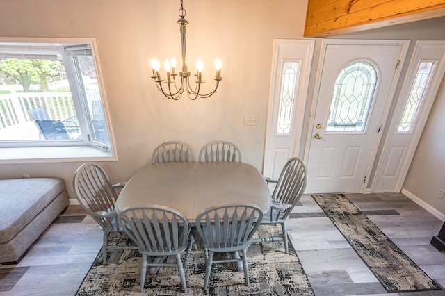 dining area with wood-type flooring, plenty of natural light, and an inviting chandelier