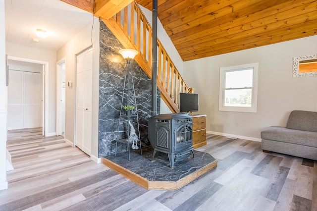 unfurnished living room featuring vaulted ceiling, hardwood / wood-style floors, a wood stove, and wood ceiling