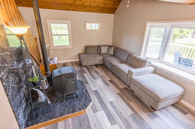 living room featuring vaulted ceiling, wood-type flooring, a wood stove, and wooden ceiling