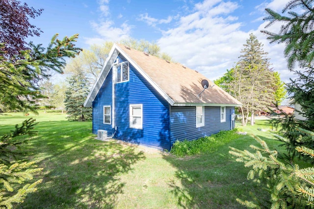 view of side of home featuring central AC unit and a yard