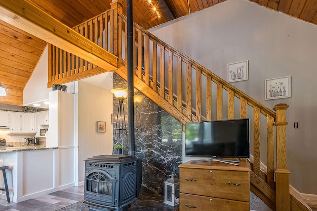 living room featuring high vaulted ceiling, wooden ceiling, a wood stove, and dark hardwood / wood-style floors