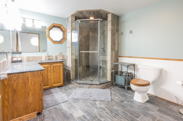 bathroom featuring a shower with door, toilet, and vanity