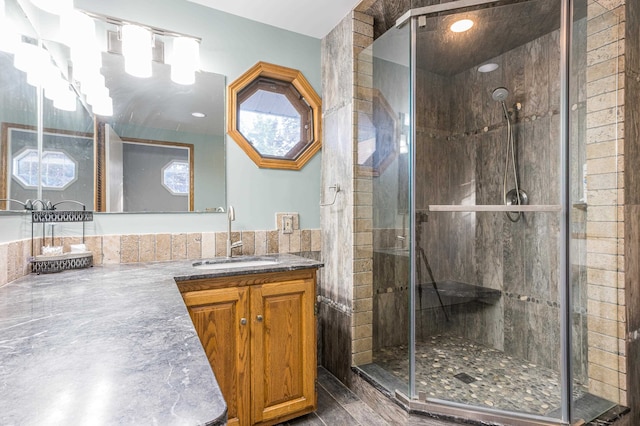 bathroom with a shower with shower door, oversized vanity, and tile walls