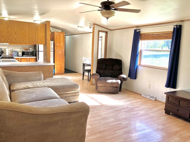 living room with ceiling fan, sink, light hardwood / wood-style flooring, and crown molding