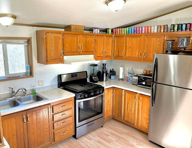 kitchen featuring appliances with stainless steel finishes, sink, ornamental molding, and light wood-type flooring