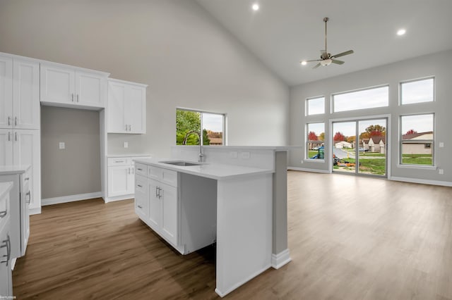 kitchen with white cabinets, ceiling fan, hardwood / wood-style flooring, high vaulted ceiling, and sink