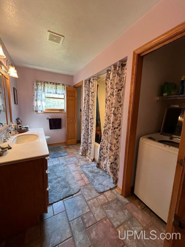 bathroom with washer / dryer, oversized vanity, a textured ceiling, and tile floors