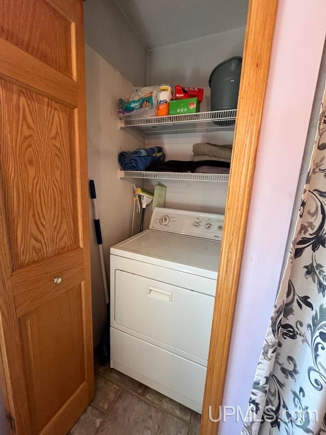 clothes washing area with washer / dryer and dark tile floors