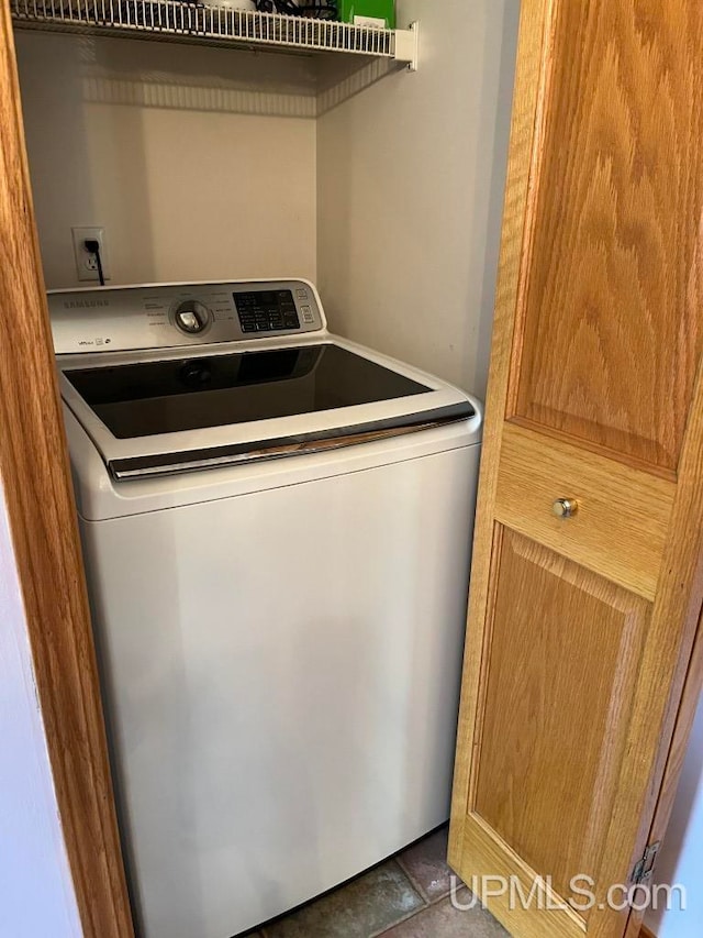 washroom featuring dark tile flooring and washer / dryer