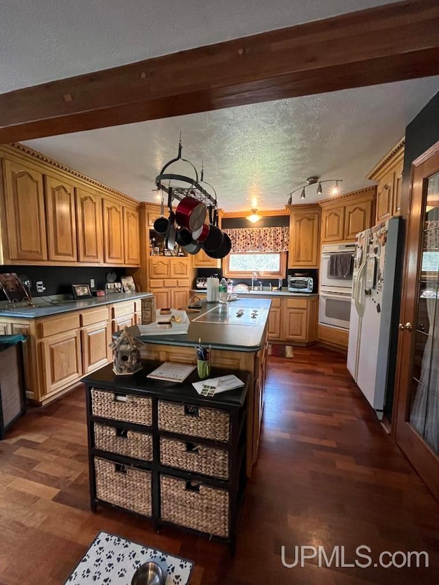 kitchen featuring white appliances, dark wood-type flooring, a textured ceiling, a kitchen island, and sink