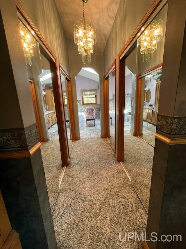 hallway featuring a chandelier, high vaulted ceiling, and carpet