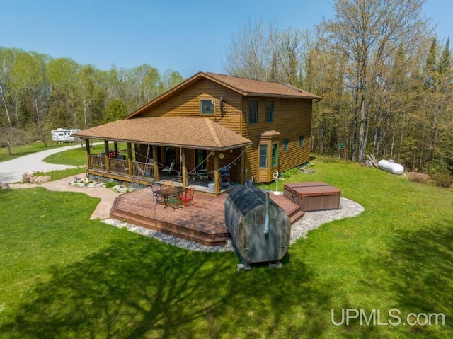 rear view of house featuring a deck, a hot tub, and a lawn