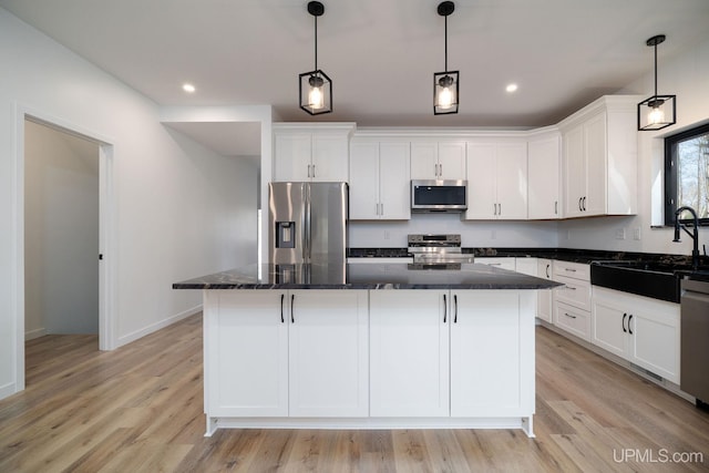 kitchen with stainless steel appliances, light wood-type flooring, a center island, and white cabinetry