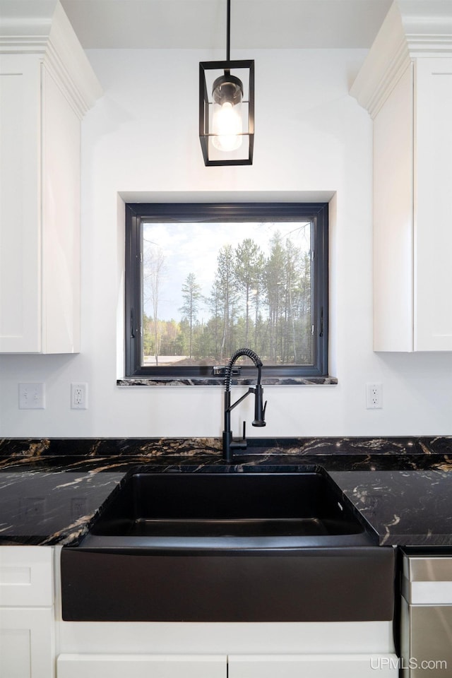 kitchen with a healthy amount of sunlight, hanging light fixtures, sink, and white cabinets