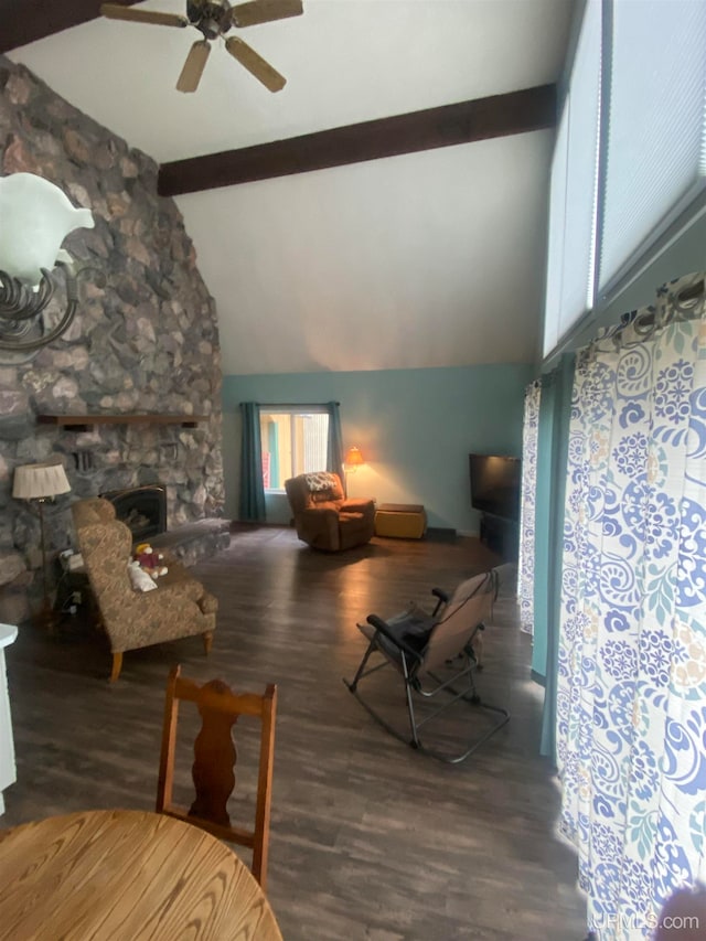 living room with ceiling fan, high vaulted ceiling, wood-type flooring, a stone fireplace, and beamed ceiling