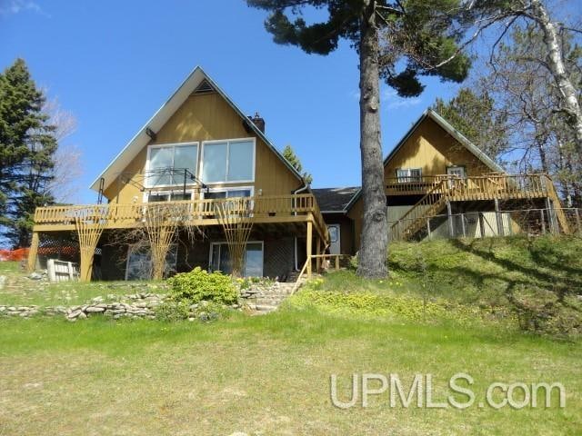 back of property with a wooden deck and a lawn