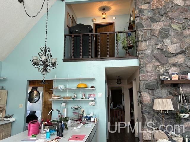 kitchen with lofted ceiling, stacked washer and clothes dryer, and a chandelier