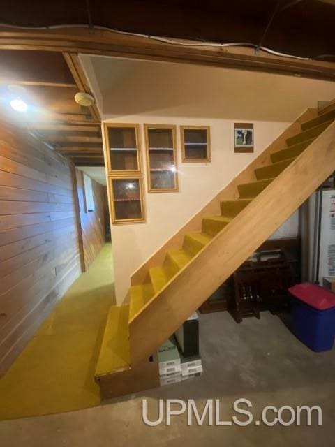 staircase featuring concrete flooring and wood walls