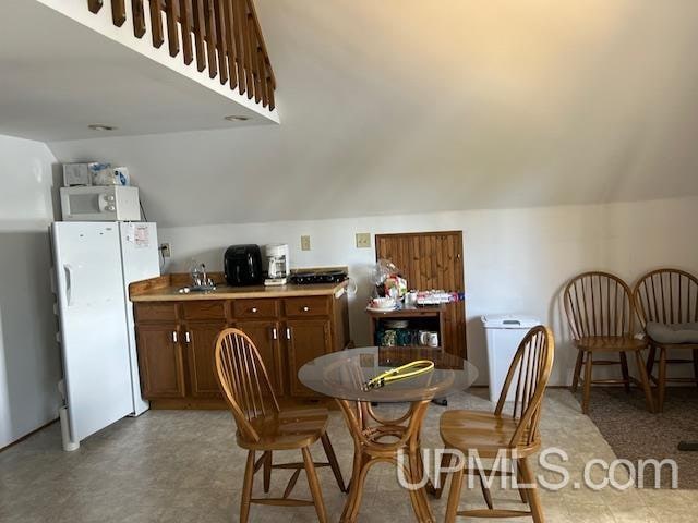 kitchen with vaulted ceiling, sink, and white appliances