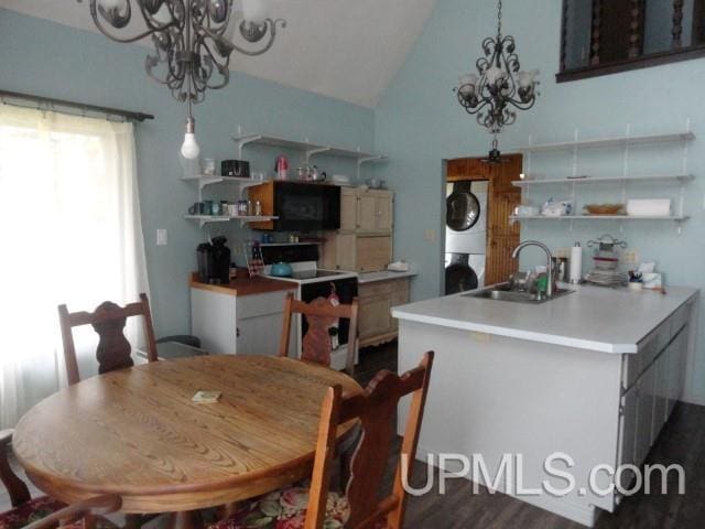 dining room with stacked washer / drying machine, sink, an inviting chandelier, vaulted ceiling, and dark hardwood / wood-style floors