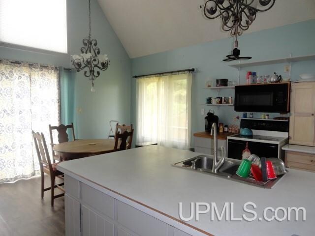 kitchen with white cabinetry, lofted ceiling, sink, a chandelier, and electric range