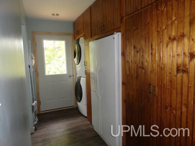 laundry room featuring stacked washer and dryer, cabinets, and dark hardwood / wood-style flooring