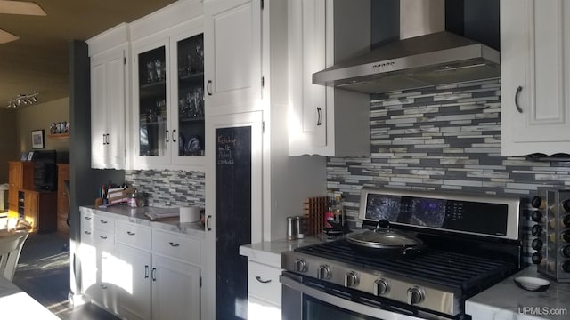 kitchen with tasteful backsplash, white cabinetry, wall chimney exhaust hood, and stainless steel gas range