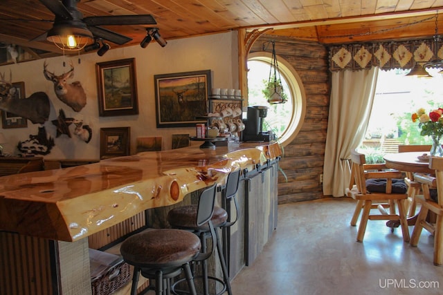 bar featuring rustic walls, ceiling fan, and wooden ceiling