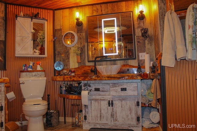 bathroom featuring wooden walls, toilet, wooden ceiling, and sink