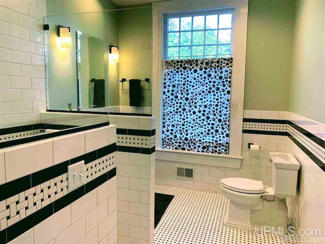 bathroom featuring tile flooring, tile walls, and toilet