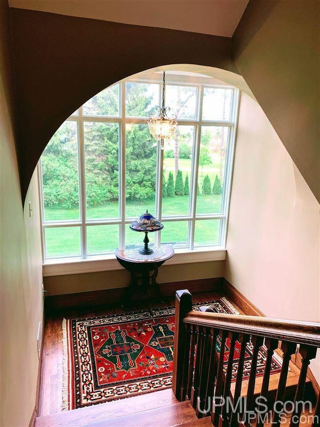 staircase featuring a healthy amount of sunlight, hardwood / wood-style flooring, and an inviting chandelier