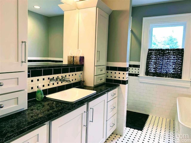 bathroom with tile walls, tile floors, large vanity, and a bathing tub