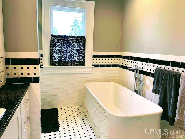 bathroom with a tub, tile flooring, tile walls, and vanity