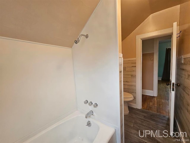 bathroom featuring toilet, hardwood / wood-style floors, bathing tub / shower combination, and lofted ceiling