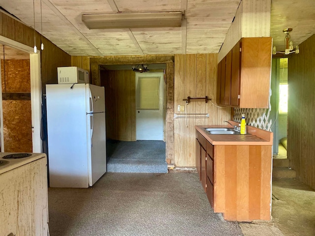 kitchen featuring wood walls, sink, white appliances, and carpet floors