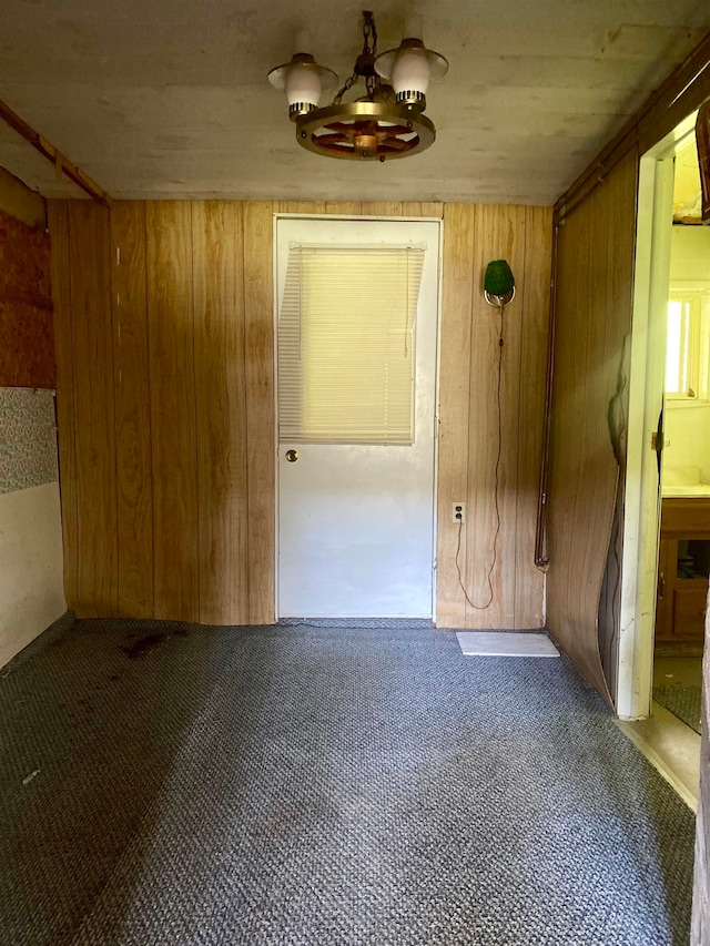 unfurnished room featuring wooden walls and carpet