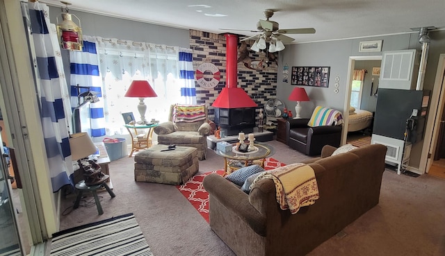 living room with ceiling fan, carpet flooring, and a wood stove