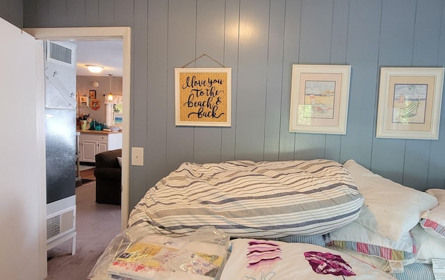 bedroom featuring dark carpet and wooden walls