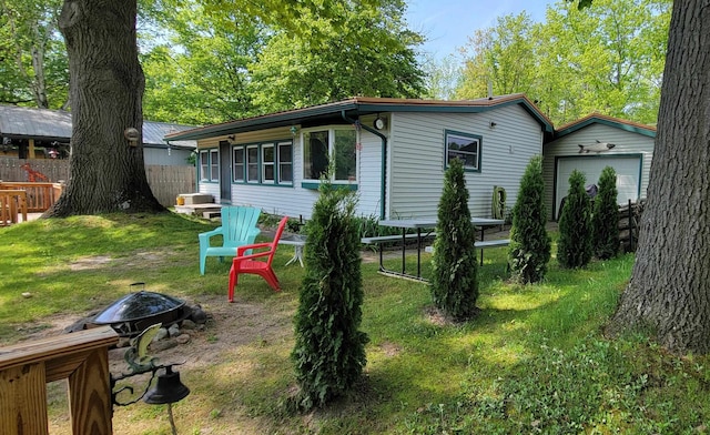 back of house with a fire pit and a yard