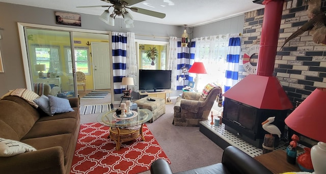 carpeted living room featuring brick wall, ceiling fan, and a wood stove