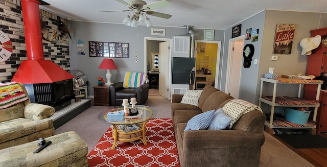 living room featuring brick wall, carpet, a wood stove, ceiling fan, and a textured ceiling