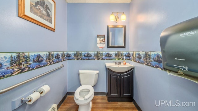 bathroom featuring a baseboard heating unit, wood-type flooring, vanity, and toilet