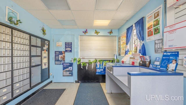 interior space with mail boxes, light tile floors, and a drop ceiling