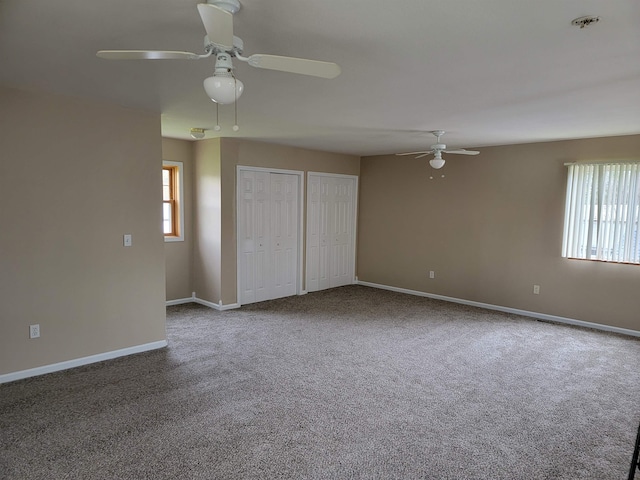 unfurnished bedroom featuring ceiling fan, carpet flooring, and multiple closets